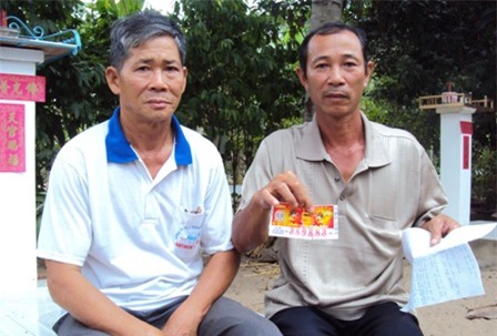 Ông Tùng (phải) và tờ vé số rách không thể lĩnh thưởng