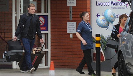 Rooney khệ nệ tay xách vali quần áo cho vợ, tay xách nôi em bé, đi sau bà xã ra xe.