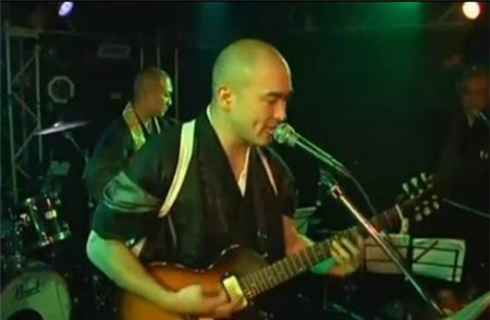 Một thầy tu trong ban nhạc đang biểu diễn trên sân khấu. Ảnh chụp từ video