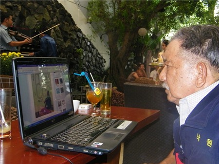 Mạc Can bên chiếc Laptop cũ kỹ.