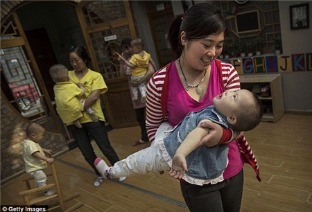 Một nhân viên chăm sóc của Trung Quốc mang một cô gái trẻ mồ côi tại một trung tâm chăm sóc nuôi dưỡng hình hôm nay tại Bắc Kinh, Trung Quốc