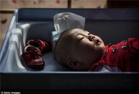 Tương lai không chắc chắn: Một cô gái trẻ mồ côi Trung Quốc đặt trên bàn thay đổi ở trung tâm Bắc Kinh