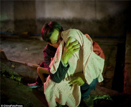 Một người đàn ông giữ em bé của mình khóc trước mặt em bé nở Quảng Châu sau khi em bé đã bị từ chối bởi vì nó quá cũ
