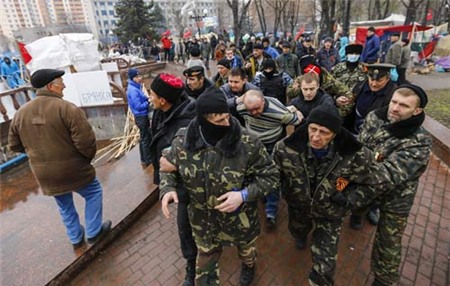 [Caption]Pro-Russian protesters escort a man detained yesterday, who they said provoked them by trying to sell a pistol, near the seized office of the SBU state security service in Luhansk, in eastern UkraineApril 13, 2014. The man was handed over to local police. Government buildings in several towns in the Donetsk and Luhansk regions were attacked in what Washington said were moves reminiscent of the events that preceded Russia's annexation of Ukraine's Crimean peninsula. REUTERS
