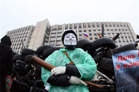 [Caption] A pro-Russian activist wearing a Guy Fawkes mask and holding a bat guards a barricade outside the regional government building in the eastern Ukrainian city of Donetsk on April 13, 2014. Cũng trong ngày hôm nay, một nhóm khoảng 40 người mang theo gậy gỗ cố gắng giành quyền kiểm soát văn phòng công tố tại thành phố Donetsk nhưng bất thành và buộc phải chấp nhận đàm phán.Các tòa nhà chính phủ ở hai thành phố nói tiếng Nga là Donetsk và Luhansk đã bị những người theo chủ nghĩa ly khai chiếm đóng từ tuần trước. Theo giới lãnh đạo thân châu Âu tại Kiev, đây là một phần trong kế hoạch chia rẽ Ukraine của Nga, tương tự như Nga từng áp dụng để sáp nhập Crimea. Theo đó, việc chiếm đóng các tòa nhà chính phủ và căn cứ quân sự được tiến hành nhằm tổ chức một cuộc trưng cầu dân ý.