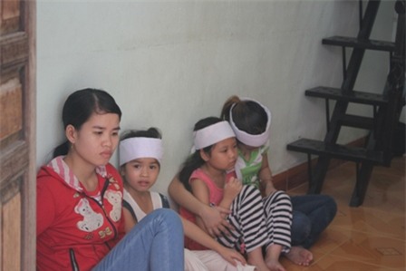 Bé gái 7 tuổi (áo đỏ, quần sọc) rầu rĩ bên xác mẹ và em