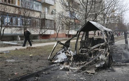 Một chiếc xe cháy rụi sau khi trúng pháo kích ở Mariupol hôm 24-1. Ảnh: Reuters