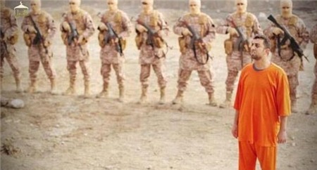Phi công Kasasbeh đứng trước một nhóm phiến quân IS có vũ trang và trùm kín mặt. Lần này, phiến quân IS hành quyết tù binh không phải bằng biện pháp cắt đầu hoặc bắn súng từ sau lưng.