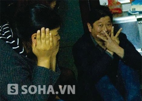 Một người đàn ông trung niên ra dấu chữ V khi bị cảnh sát đưa đi.