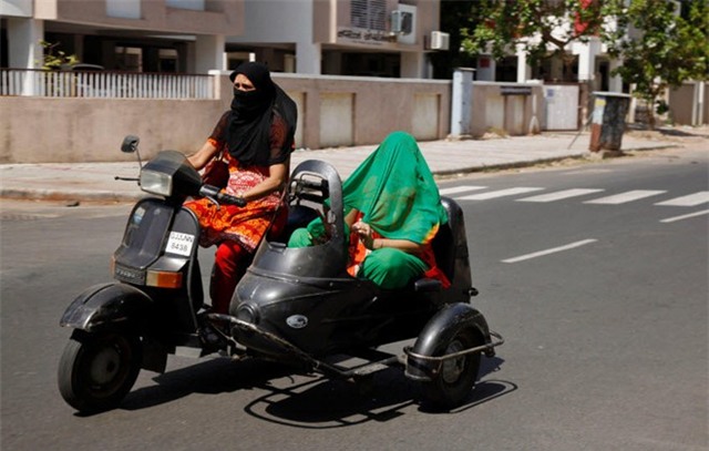 Những phụ nữ phải che khăn tránh nóng khi lái xe trên đường tại thành phố Ahmedabad, bang Gujara. Theo trang NDTV, hơn 750 người đã thiệt mạng vì trời quá nóng. Ảnh: AP