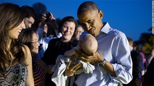 Ông chủ Nhà Trắng bế một em bé tại buổi dã ngoại của quốc hội Mỹ ở Nhà Trắng, tháng 9/2014.