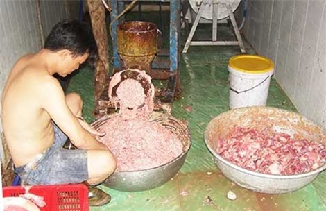 Ở trần ngồi xay thịt với máy xay rỉ sét
