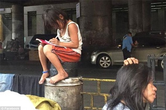 Bé gái Cielo Gonzales ngồi trên bục chắn đường mải mê làm bài tập. Ảnh: Facebook