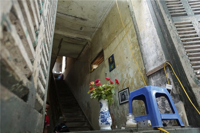 Sơn cửa bong tróc, tường nhà ẩm mốc vì dột, chiếc cầu thang gỗ nối lên tầng 2 khá ọp ẹp do không được sửa chữa.