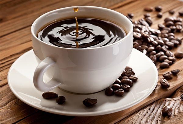Drop falling into a cup of coffee. On a wooden background