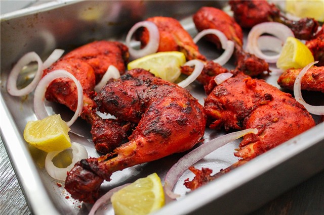Gà Tandoori (Ấn Độ): Có xuất xứ ờ vùng Punjab từ thời Mughal, món gà Tandoori được làm từ thịt gà ướp hỗn hợp sữa chua và gia vị, sau đó nấu trong nồi đất. Người nấu thường cho thêm nghệ để món ăn có màu cam, hoặc ớt bột để có màu đỏ hấp dẫn. Ảnh: Earthindian.