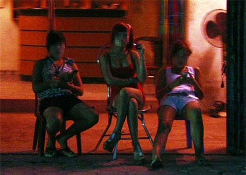 Các cô gái ngồi mời khách trước quán cà phê đèn mờ ở vùng ven Hà Nội. 