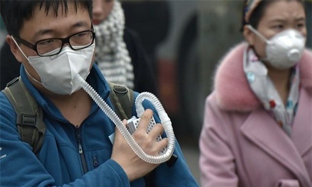 Một thanh niên mang theo máy hô hấp khi di chuyển qua trung tâm ở Bắc Kinh khi sương dày. Ảnh: Getty