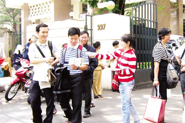 Nguyễn Thúy Hà - sinh viên ĐH Kinh tế Quốc dân (từ phải qua) chọn việc phát tờ rơi để có thu nhập mua vé tàu xe và tiêu dịp Tết. Ảnh: Q.A
