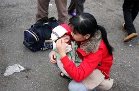 Một phụ nữ bế con đợi xe về quê ăn Tết