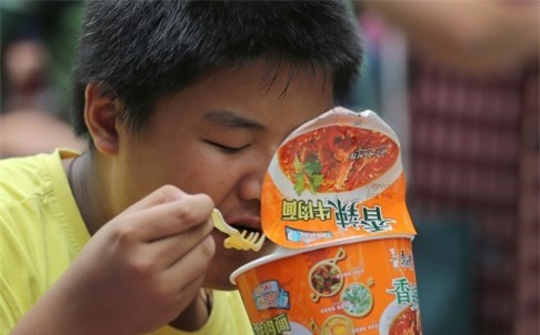  Một bé trai vội ăn bát mỳ khi đang chờ tàu ở nhà ga tại Bắc Kinh. Ảnh: AP