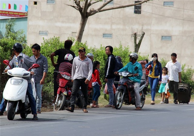 Nhiều người đứng ven quốc lộ 1A ở xã Thạnh Phú, huyện Mỹ Xuyên (Sóc Trăng) để đón xe đi TP HCM sáng 13/2. Ảnh: Việt Tường.