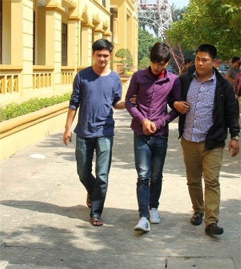 Phạm Minh Vương (giữa) dẫn giải về trụ sở công an