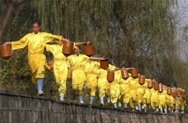 Nhóm học viên học võ Thiếu Lâm rèn luyện sức khỏe bằng cách nhấc hai thùng nước tại một ngôi chùa ở Đăng Phong.