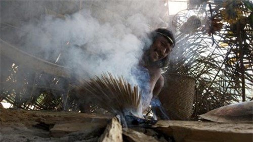 Một thổ dân Waorani đang hơ mũi tên trên lửa.