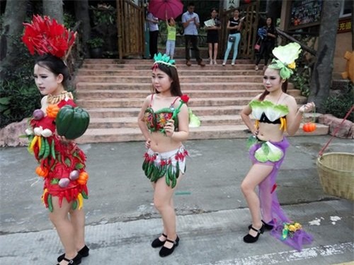 Vai trần, hở lưng hở bụng khoe chân dài trong trang phục rau củ quả chẳng giống ai, dàn mẫu trẻ gây náo loạn đường phố khi xuống đường đi theo nhịp chiêng trống, vừa múa vừa hát rất vui vẻ.