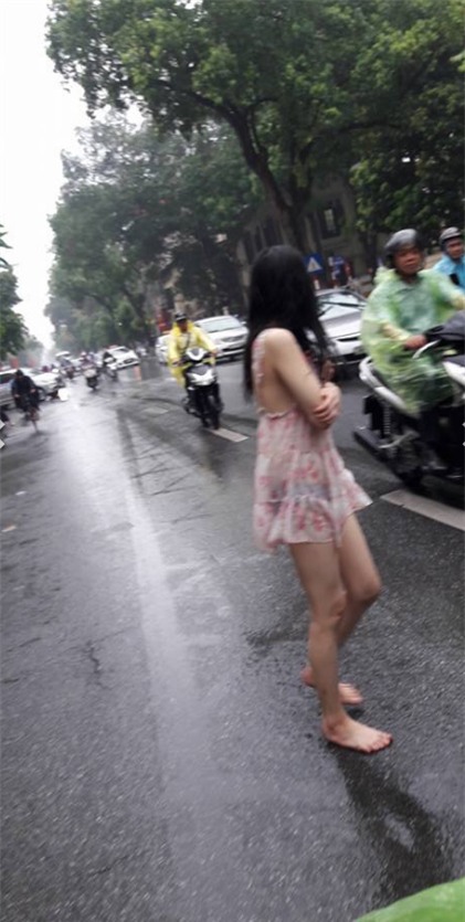 Hành động quá khó hiểu của cô gái giữa phố Hà Nội ngày mưa - Ảnh 1.
