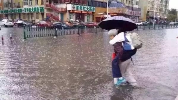 Bức ảnh bà lội nước cõng cháu gái lớn bổng đi học khiến dư luận dậy sóng - Ảnh 2.