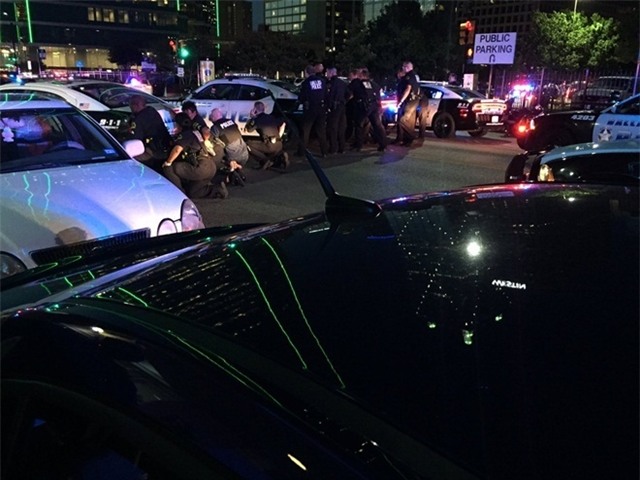 Cảnh sát Dallas nấp sau các xe ô tô tại khu thương mại Lamar để vây bắt kẻ tình nghi (Ảnh: Telegraph)