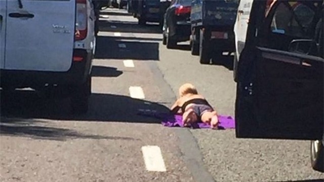 Dù giữa thời điểm ánh nắng và nhiệt độ cao nhất trong năm, cô gái vẫn thản nhiên nằm úp lưng xuống đường 