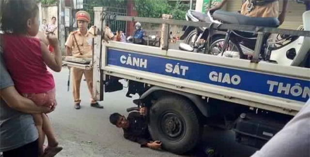 Nam thanh niên nằm ôm bánh xe ô tô của CSGT để 
