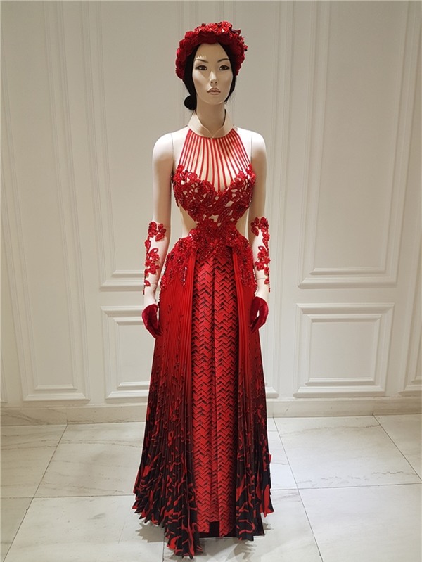 Công Trí kết hợp ren cùng chất liệu xuyên thấu để tạo nên bức tranh họa tiết cầu kì từ ngực trải dài xuống thắt eo. Kết hợp cùng bộ trang phục là chiếc mấn đội đầu thực hiện hoàn toàn bằng phương pháp thủ công.