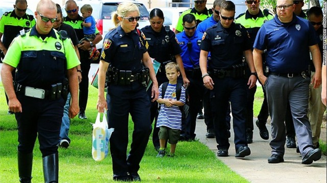 Câu chuyện buồn đằng sau bức hình em bé 4 tuổi đi khai giảng với 18 cảnh sát theo sau - Ảnh 1.