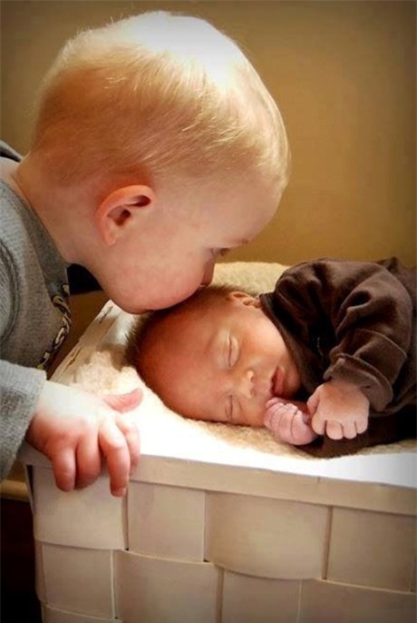 Cậu bé đặt một nụ hôn lên đứa em nhỏ xíu của mình. (Ảnh: Internet)