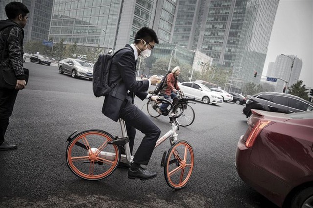 Một người đàn ông đang sử dụng xe đạp của công ty Beijing Mobike ở Bắc Kinh. Ảnh: Bloomberg