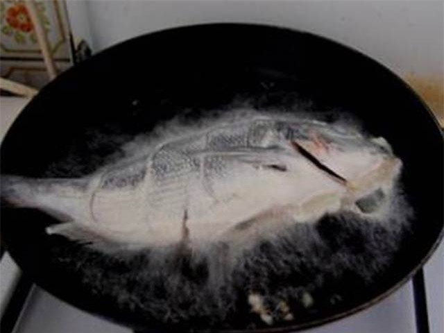 Cá sau khi lăn qua lớp bột chiên cho vào chảo.