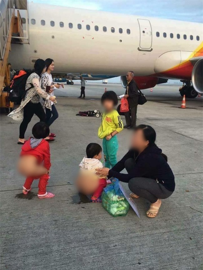 Người mẹ hồn nhiên cho 2 bé gái đi vệ sinh ngay giữa đường băng máy bay - Ảnh 1.