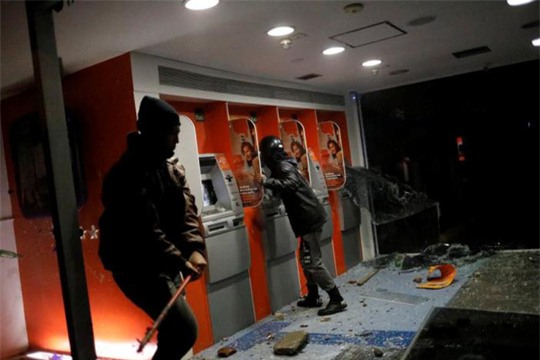 Người biểu tình đập phá ATM. Ảnh: Reuters