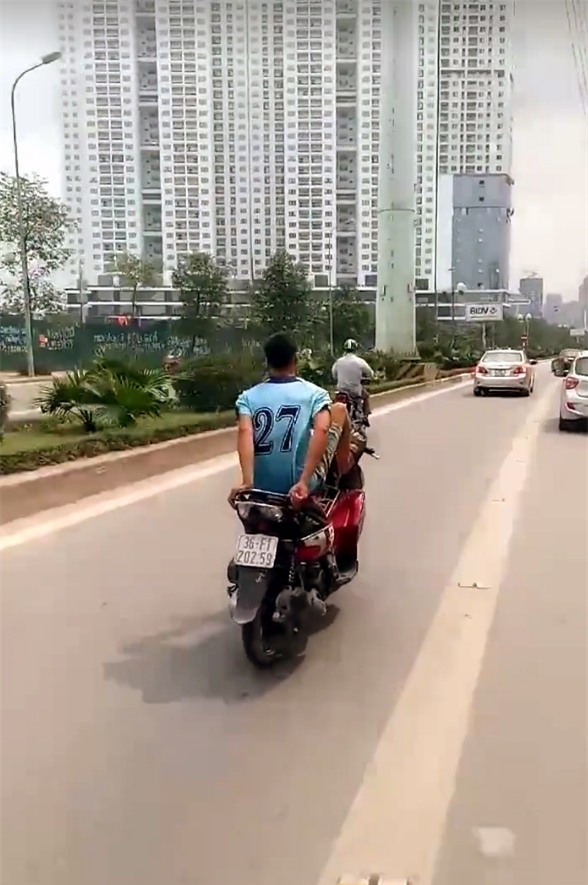 Nam thanh niên đi xe máy bằng chân trên làn BRT. (Ảnh cắt từ clip)