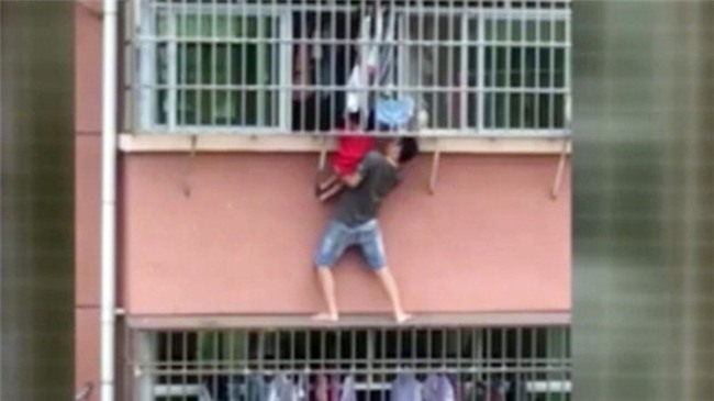 Mạo hiểm cứu bé trai treo lủng lẳng ở cửa sổ nhà cao tầng - Ảnh 1.