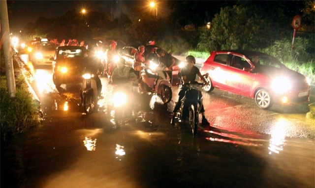 Dòng ô tô, xe máy chùn chân ga, đứng chờ trước hồ nước.