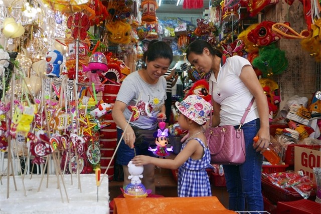 Bé gái được mẹ đưa đi mua đồ chơi Trung thu sớm ở một cửa hàng trên phố Hà Mã.