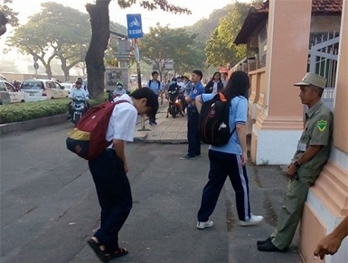 Học sinh lễ phép chào người đàn ông làm nhiệm vụ bảo vệ trước cổng trường.