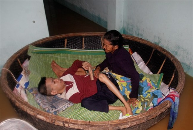 Quặn lòng cảnh mẹ 72 tuổi neo thúng giữ con chất độc da cam giữa lũ - Ảnh 1.