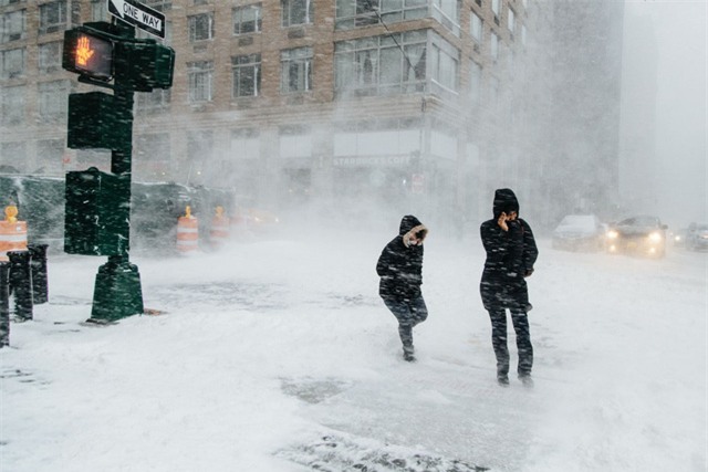 “Bom bão tuyết” khiến nhiều khu vực ở thành phố New York chìm trong khối tuyết dày, trong khi tại New England, ước tính cứ một giờ tuyết sẽ dày thêm 8 cm. Trong ảnh: Người đi bộ “chống chọi” với gió tuyết để qua đường ở New York. (Ảnh: EPA)