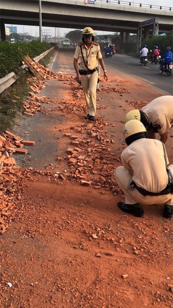 Hành động đẹp: CSGT TP.HCM dùng tay dọn dẹp từng viên gạch từ xe đầu kéo gặp nạn trên đường - Ảnh 1.